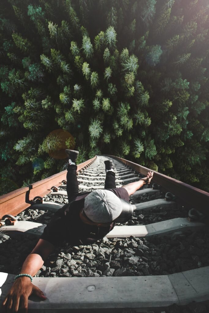 pexels-photo-1732370-1732370 A man poses daringly over train tracks with a forest view.